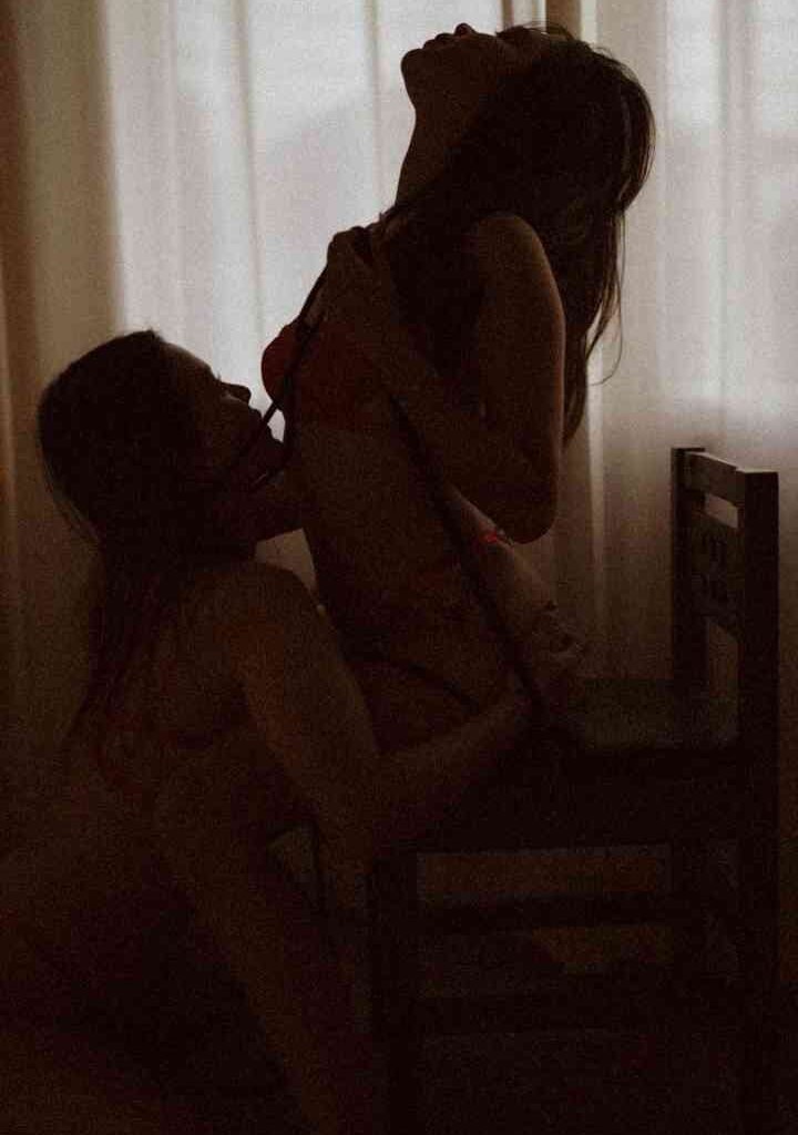 KL Escort Girl Silhouetted figures of two women in intimate embrace, one seated on a chair Malaysia Escort Sex in Kuala Lumpur