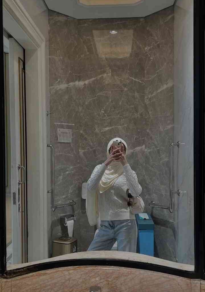 KL Escort Girl A woman in a hijab takes a mirror selfie in a modern bathroom. Malaysia Escort Sex in Kuala Lumpur